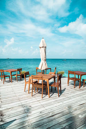 empty outdoor wood table and chair with sea view background in Maldivesのeditorial素材