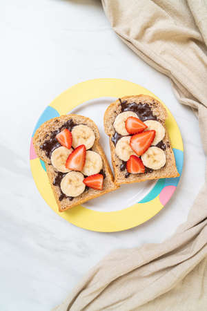 whole wheat bread toasted with fresh banana, strawberry and chocolate for breakfastの写真素材