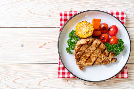 grilled and barbecue fillet pork steak with corn, carrot and tomatoesの写真素材