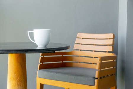coffee cup on table with empty chair
