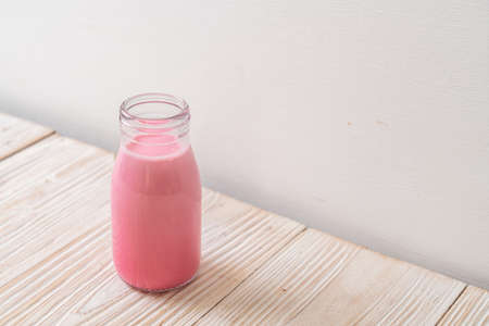 pink milk or strawberry milk in bottle on wood background