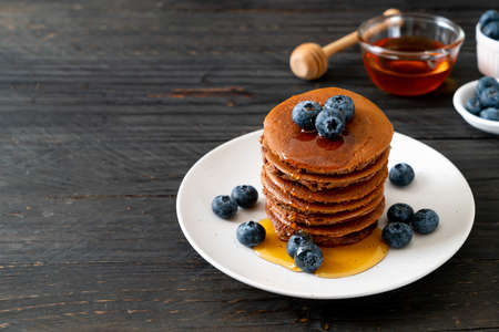 chocolate pancake stack with blueberry and honey on plateの写真素材