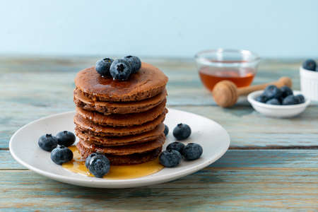 chocolate pancake stack with blueberry and honey on plateの写真素材