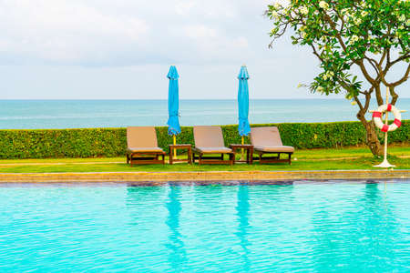 chair pool and umbrella around swimming pool with ocean sea backgroundのeditorial素材