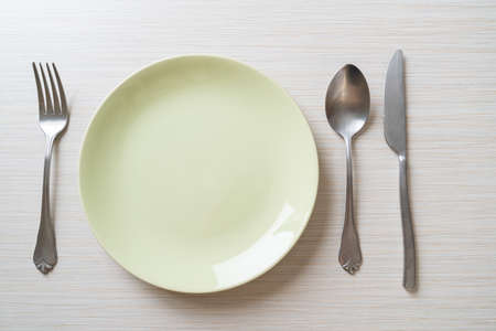 empty plate or dish with knife, fork and spoon on wood tile backgroundの写真素材