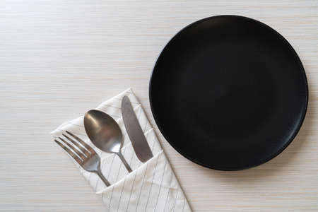 empty plate or dish with knife, fork and spoon on wood tile background