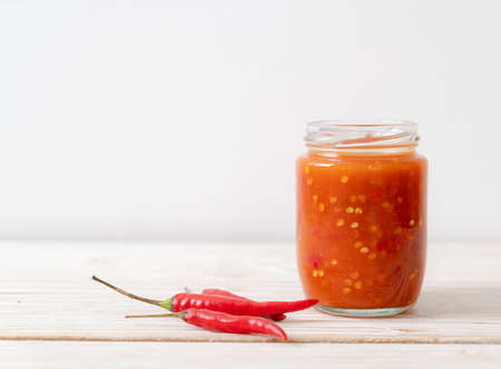 chilli or chilli sauce in bottle and jar on wwod background
