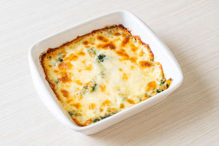 baked spinach lasagna with cheese in white plateの写真素材