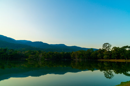 Ang Kaew lake at Chiang Mai University with forested mountain and twilight skyの写真素材