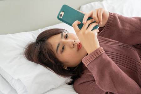 beautiful Asian women playing smartphone on bedの写真素材
