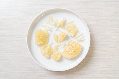 Fresh peeled pomelo, grapefruit or shaddock on white plateの写真素材