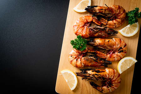 grilled tiger prawns or shrimps with lemon on wood boardの写真素材