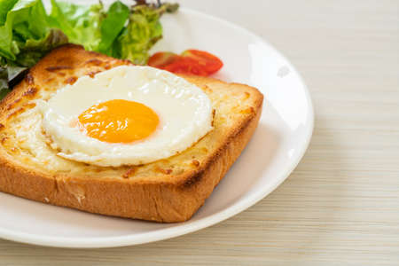 homemade bread toasted with cheese and fried egg on top with vegetable salad for breakfastの写真素材