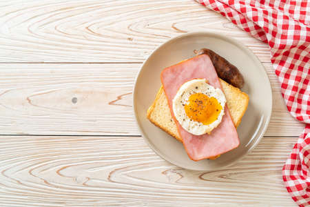 homemade bread toasted cheese topped ham and fried egg with pork sausage for breakfastの写真素材