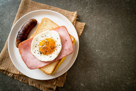 homemade bread toasted cheese topped ham and fried egg with pork sausage for breakfastの写真素材