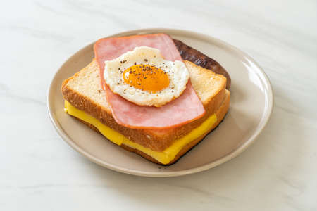 homemade bread toasted cheese topped ham and fried egg with pork sausage for breakfastの写真素材