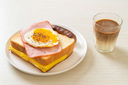 homemade bread toasted cheese topped ham and fried egg with pork sausage and coffee for breakfastの写真素材