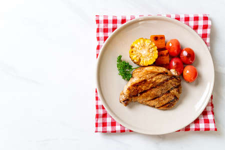 grilled and barbecue fillet pork steak with corn, carrot and tomatoesの写真素材