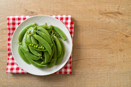 fresh sweet green peas on white plateの写真素材
