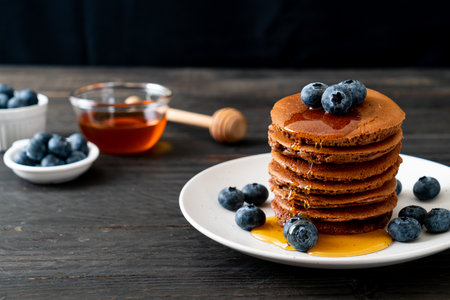 chocolate pancake stack with blueberry and honey on plateの写真素材