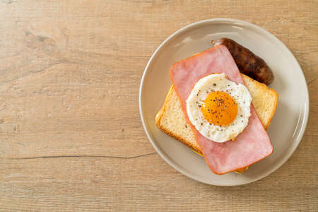 homemade bread toasted cheese topped ham and fried egg with pork sausage for breakfastの写真素材