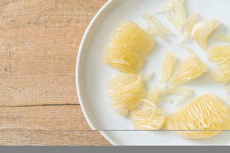 Fresh peeled pomelo, grapefruit or shaddock on white plate