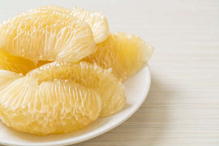 Fresh peeled pomelo, grapefruit or shaddock on white plateの写真素材