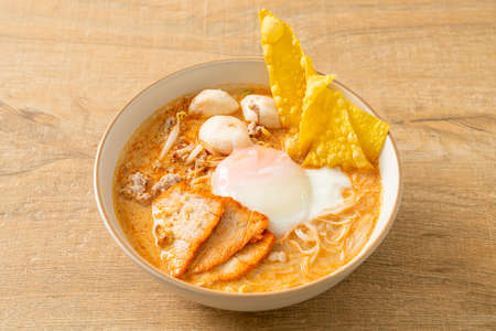 Rice vermicelli noodles with meatball, roasted pork and egg in spicy soup - Tom Yum Noodlesの写真素材