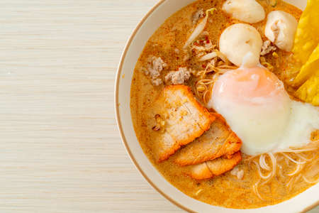 Rice vermicelli noodles with meatball, roasted pork and egg in spicy soup - Tom Yum Noodlesの写真素材