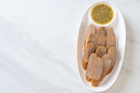 fried Chinese fish cake or fish ball line sliced with spicy seafood dipping sauceの写真素材