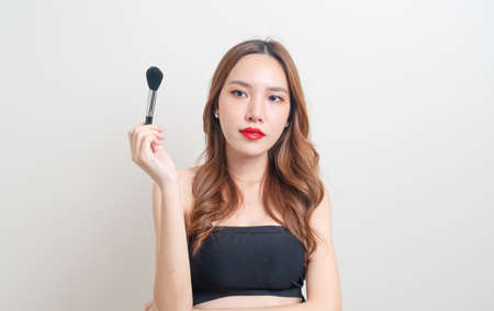 portrait beautiful Asian woman with makeup brush on white background