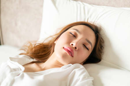 portrait beautiful Asian woman sleeping on bed with white pillowの写真素材