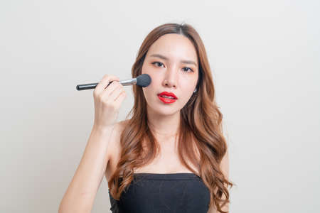 portrait beautiful Asian woman with makeup brush on white backgroundの写真素材