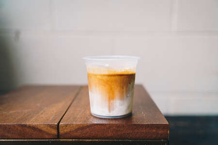 dirty coffee in takeaway glass on wood tableの写真素材