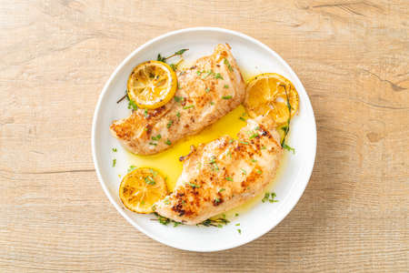 grilled chicken with butter, lemon and garlic on white plateの写真素材