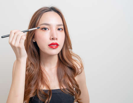 portrait beautiful Asian woman with makeup eye brush on white backgroundの写真素材