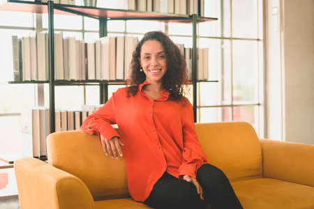 happy latin woman sitting on a comfortable sofa at home