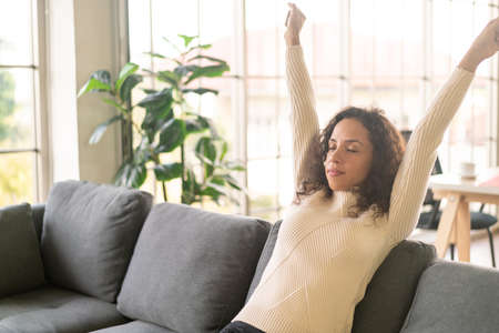Latin woman on sofa at home with lazy feelingの写真素材