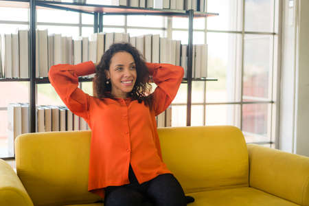 happy latin woman sitting on a comfortable sofa at homeの写真素材
