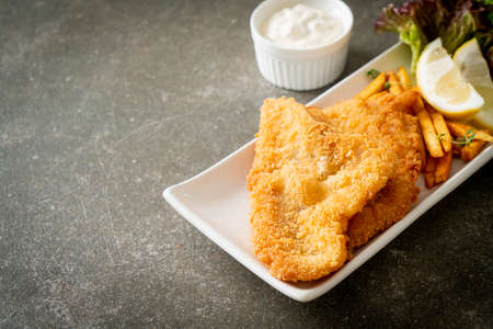 fish and chips - fried fish fillet with potatoes chips and lemon on white plate