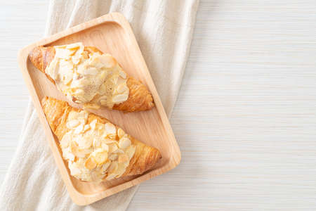 croissant with cream and almonds on wood plateの写真素材