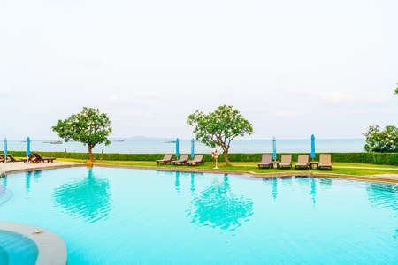 chair pool or bed pool and umbrella around swimming pool with sea beach backgroundの写真素材