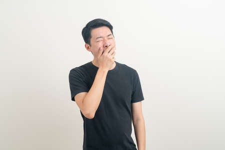 young Asian man with yawn face and sleepy on white backgroundの写真素材