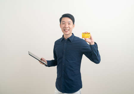 portrait young Asian man holding credit card and tablet on white backgroundの写真素材