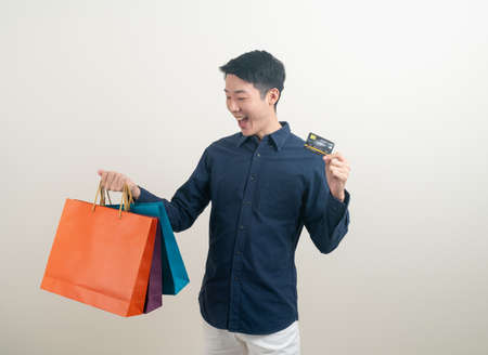 portrait young Asian man holding credit card and shopping bag on white backgroundの写真素材