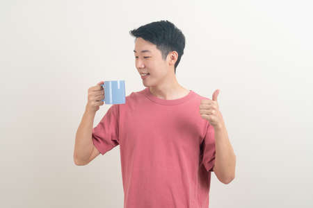 young Asian man holding coffee cup with smiling face on white backgroundの写真素材