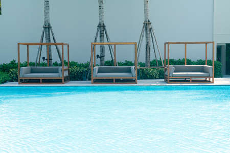 outdoor patio sofa around swimming pool - holiday and vacation concept