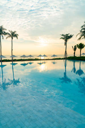umbrella with bed pool around swimming pool with ocean sea background at sunset or sunrise time - holiday and vacation conceptの写真素材