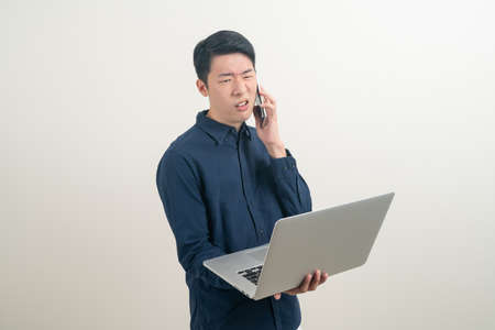 portrait young Asian man talking smartphone or mobile phone and hand holding laptop on white backgroundの写真素材