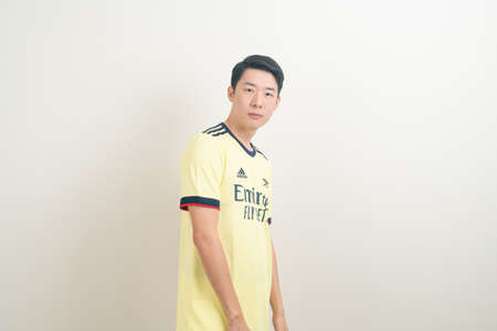 Bangkok, THAILAND - Nov 27, 2021 : Young Asian man wearing Arsenal shirt with white background. Arsenal football club is a famous team in London city.のeditorial素材